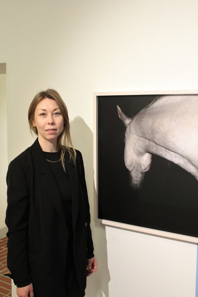 Taija Jyrkäs taustallaan Kukka-Maria Rosenlund teos.