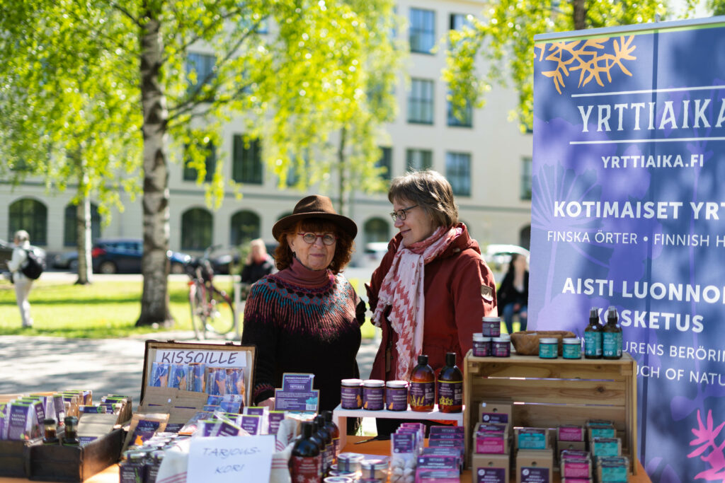 Two people at a stand in a park on a sunny day