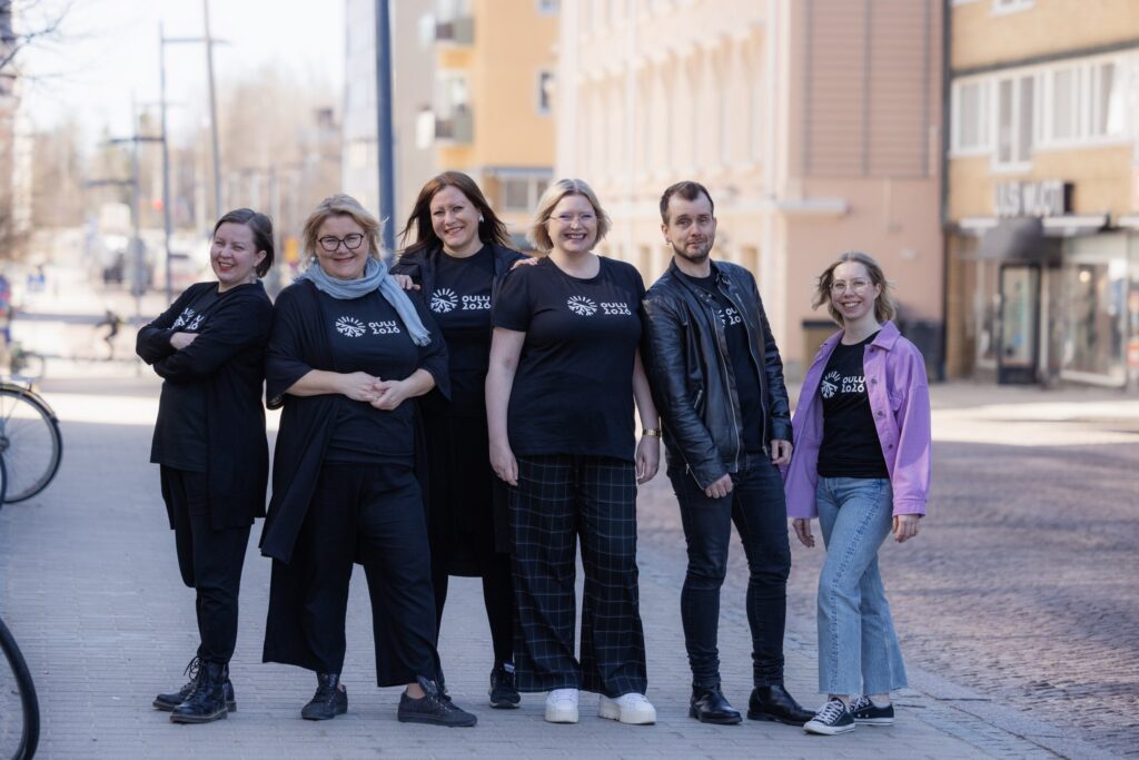 Kuvassa Oulu2026-henkilökuntaa seisomassa Torikadulla