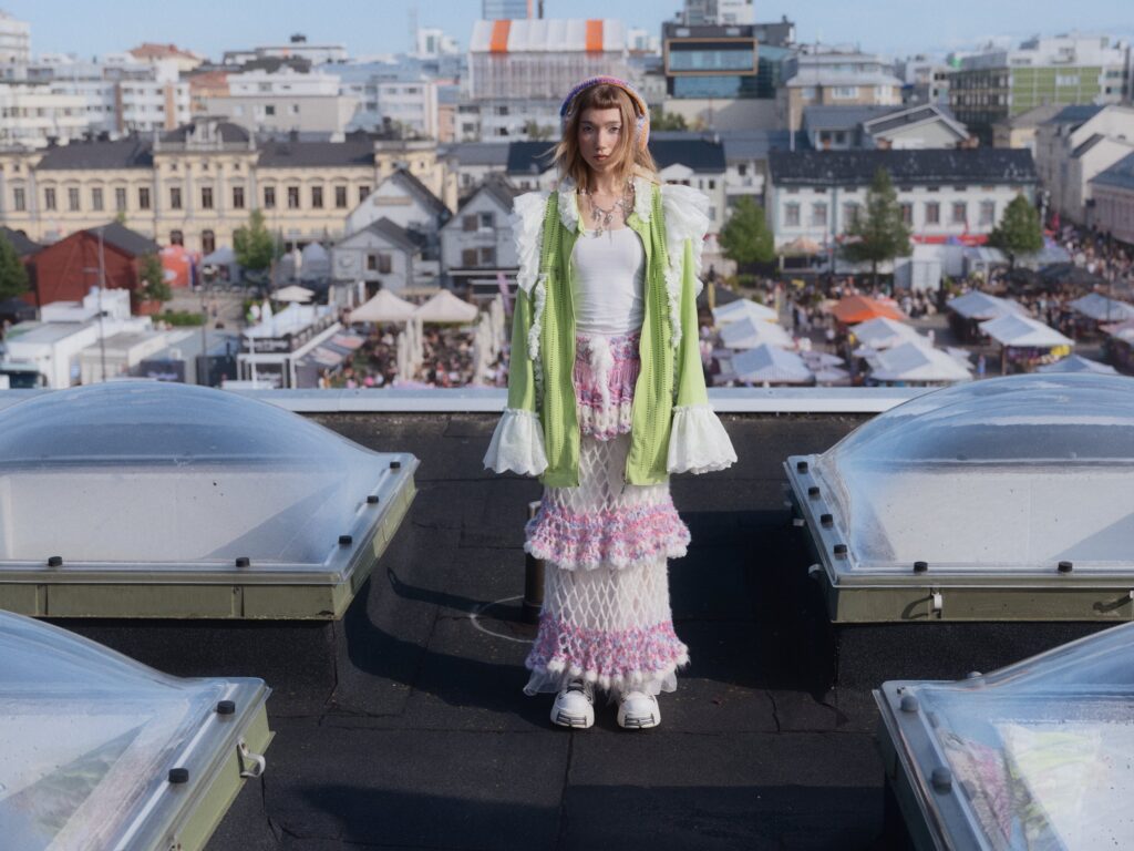 Woman on rooftop with city market background.
