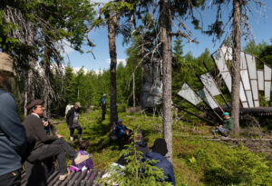Yleisöä taiteilija Petter Yxellin To the Lighthouse -teoksen äärellä Henkiolentojen kukkula -kesänäyttelyn avajaisissa Hyrynsalmella 2024. Kuvaaja: Janette Holmström.