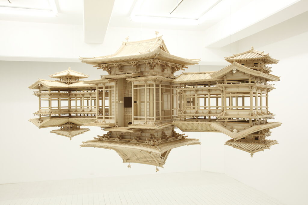 Hanging wooden architectural model in white room.