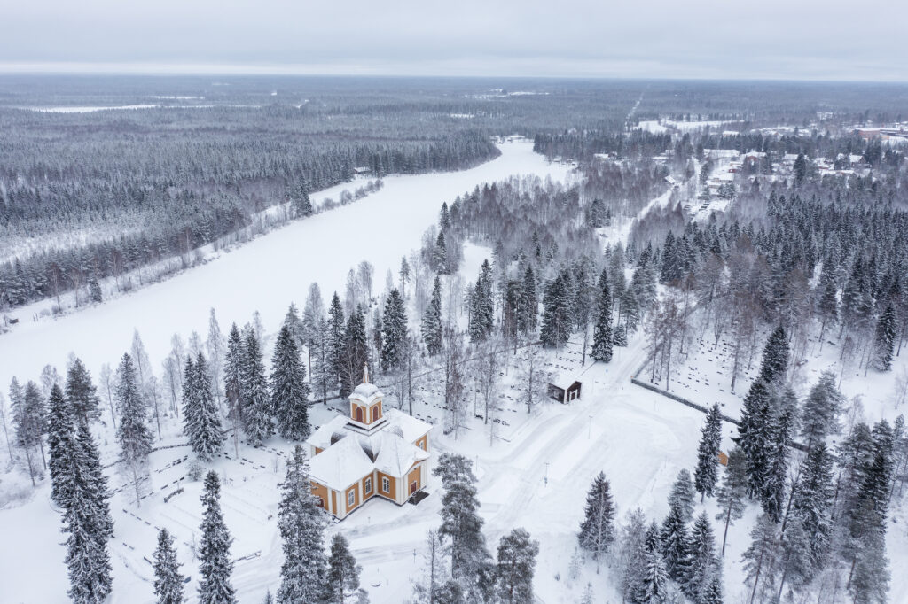 Snowy landscape of Ylikiiminki with forest and small church.