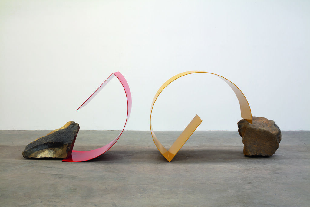 Abstract metal and rock sculptures on concrete floor.