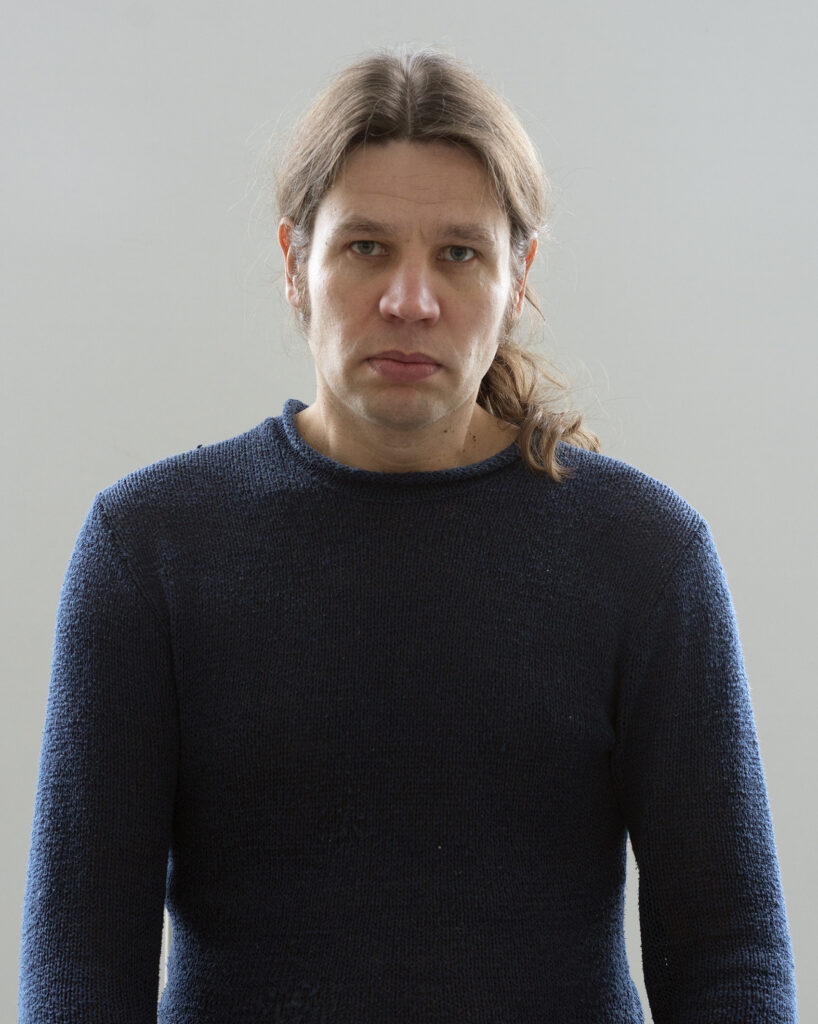 Person in blue jumper with neutral expression.
