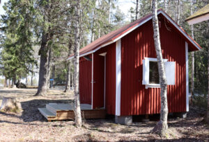 kuvassa punainen pieni mökki metsässä
